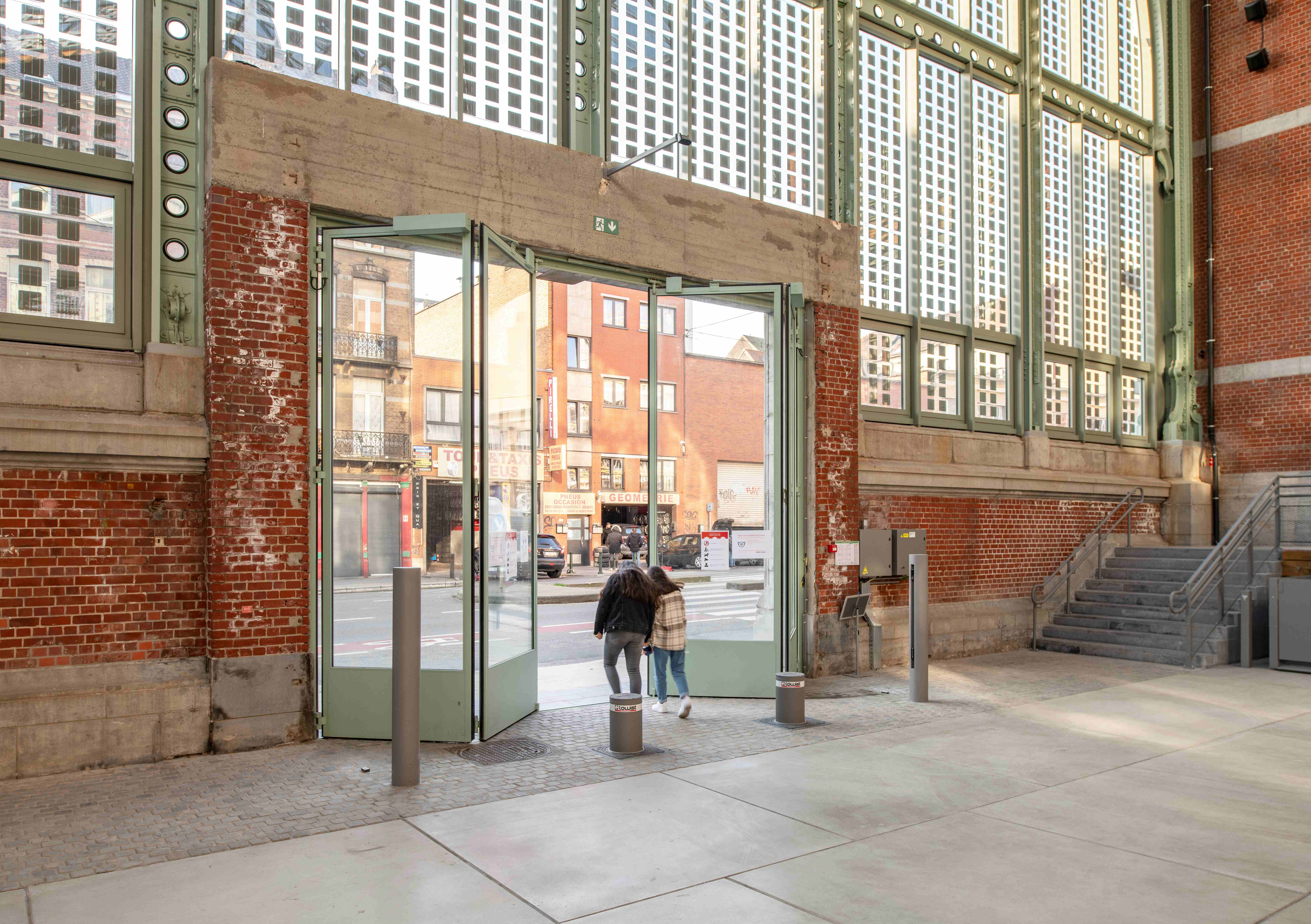 Stalen vouwdeuren in vier panelen, twee aan twee gevouwen, geïntegreerd in de wand met fotovoltaïsche zonnecellen, Gare Maritime Brussel - Lootens