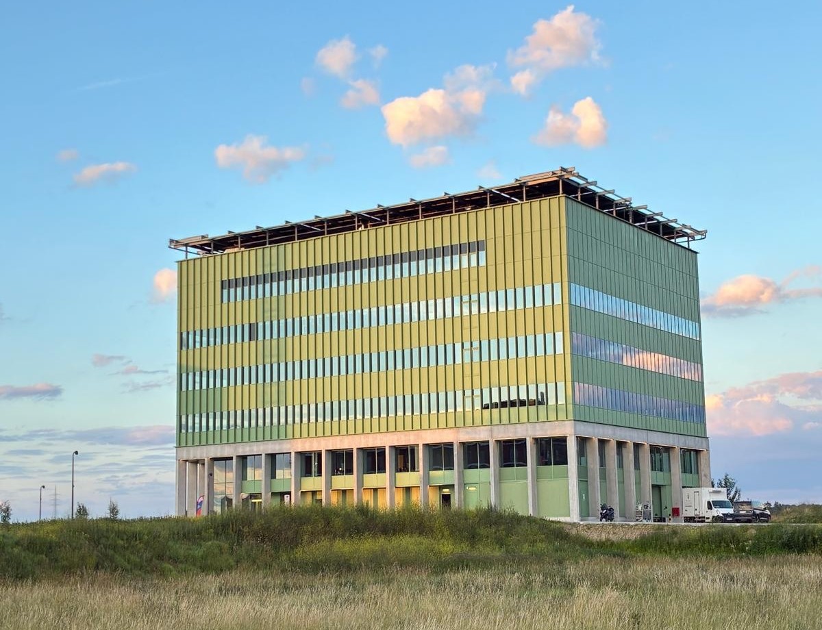 Vliesgevel in aluminium schrijnwerk van Lootens. Groen getint doorzichtglas afgewisseld met lichtgroene borsweringen. Dus afwisselend donkergroene en lichtgroene lijnen. Zomers gevoel.